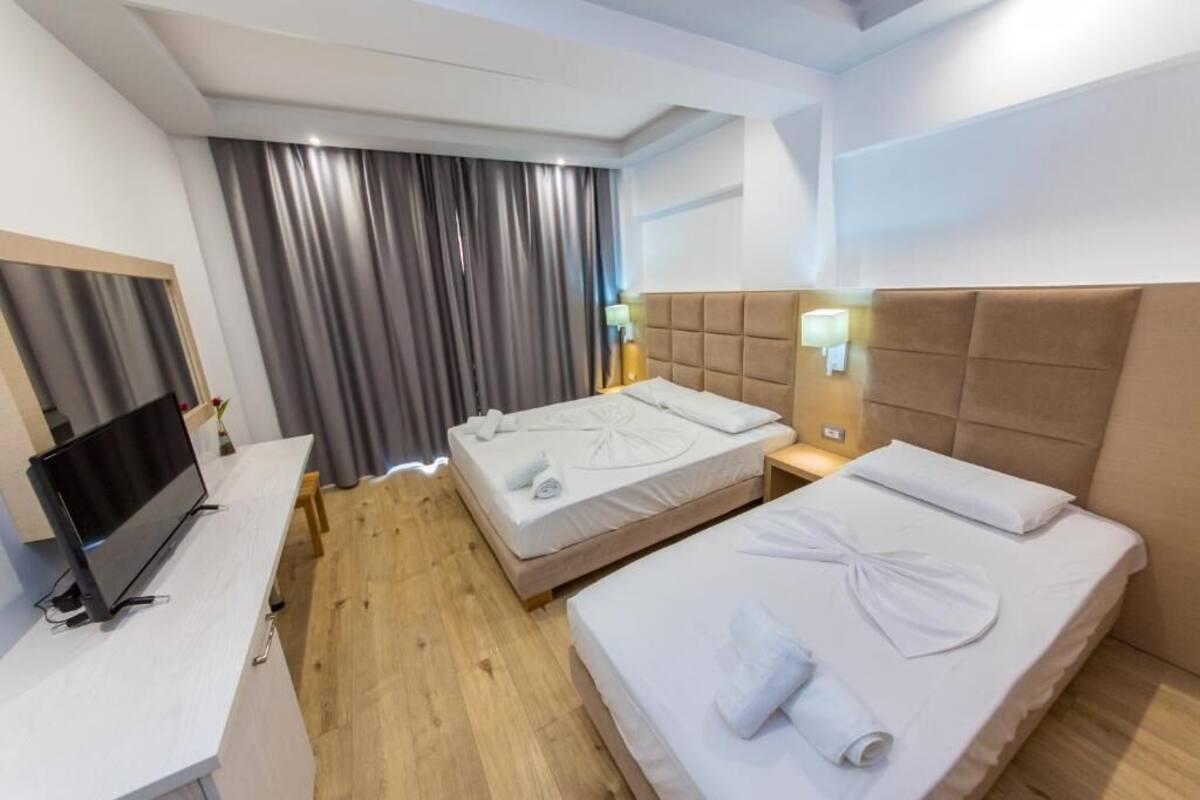 A hotel room with two beds, a TV, and a desk.