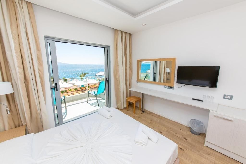 Habitación de hotel con cama, televisión, escritorio pequeño y vista al océano.