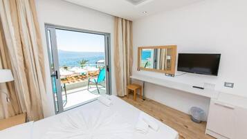 Habitación de hotel con cama, televisión, escritorio pequeño y vista al océano.