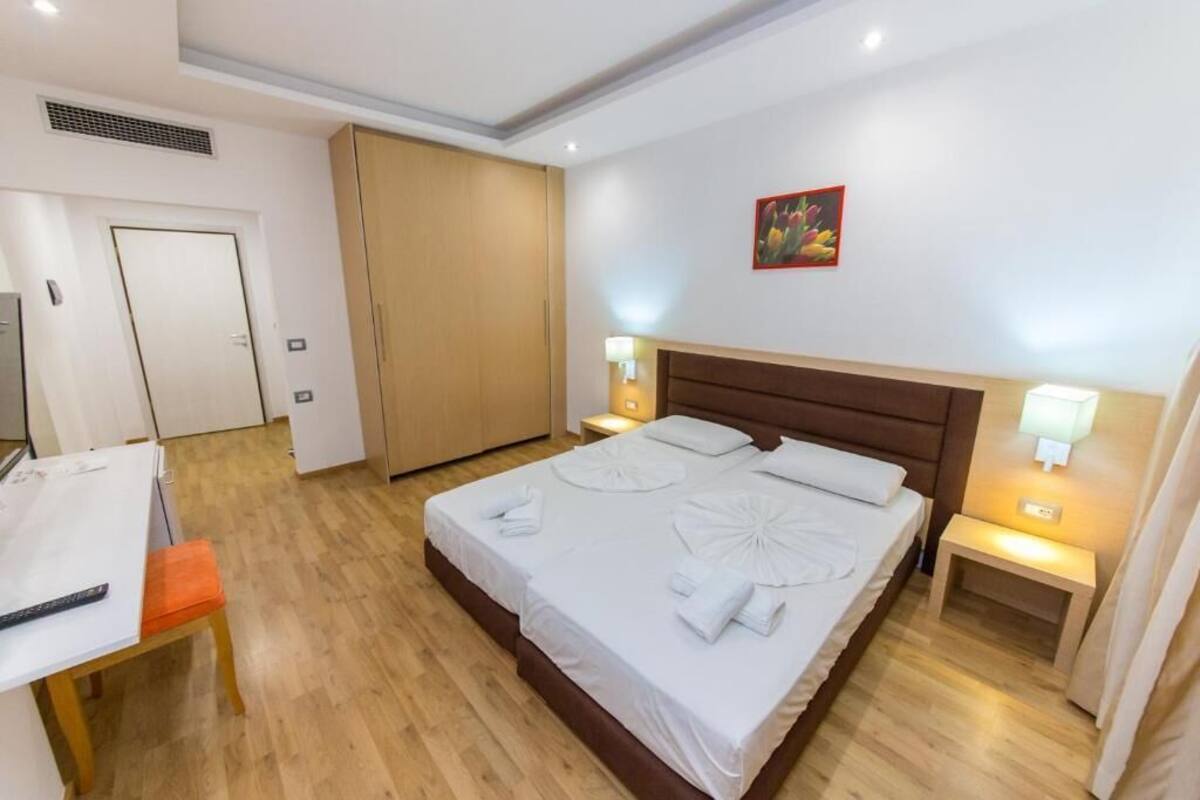 A hotel room with a bed, bedside tables, a desk, and a wardrobe.