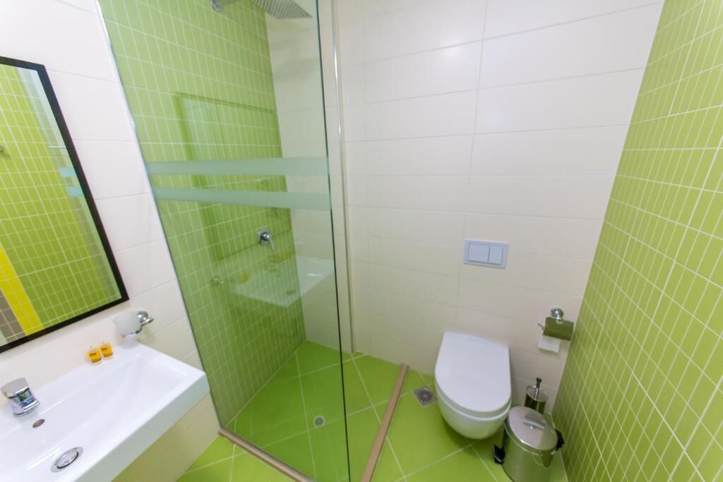 A bathroom with a glass-enclosed shower, a white sink, and a toilet.