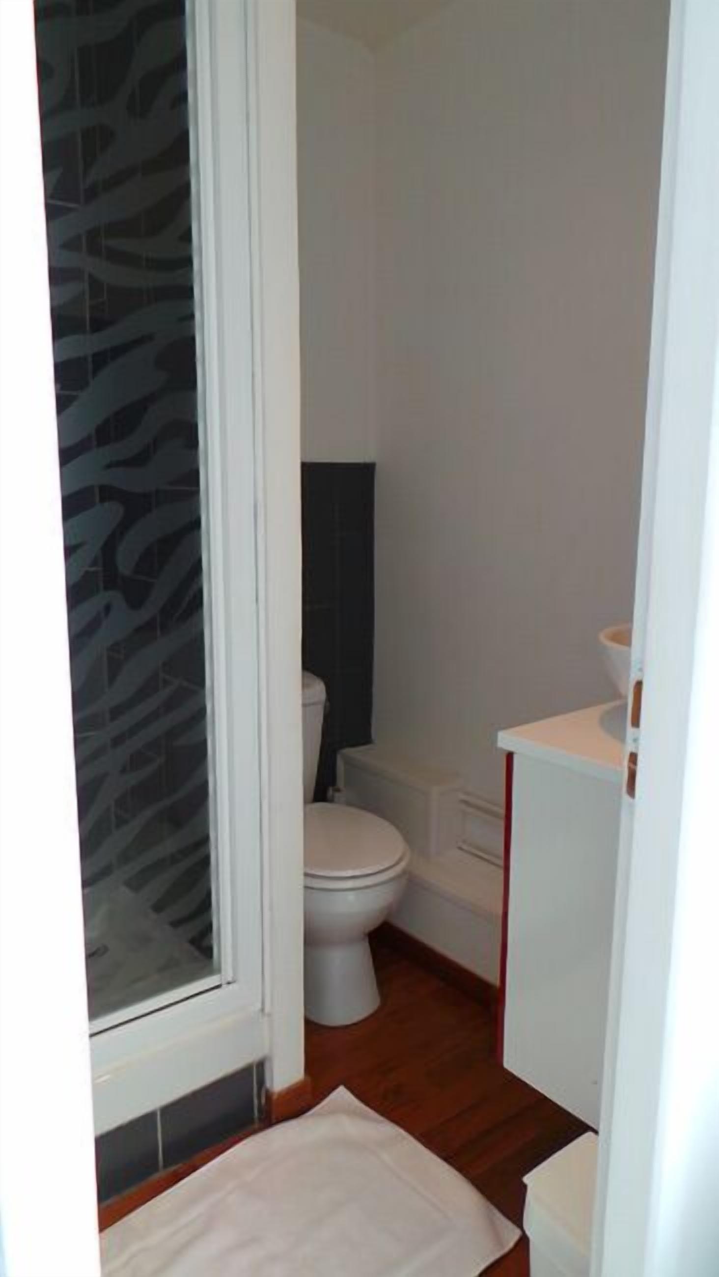 Une petite salle de bain comprenant des toilettes, un lavabo et un espace douche.