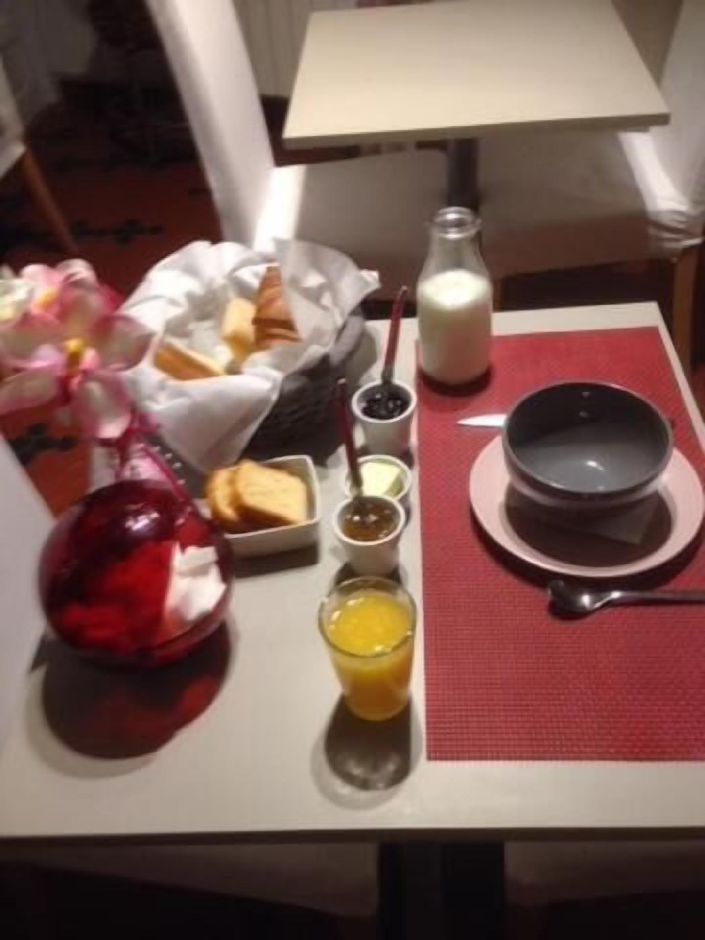 A breakfast table with a bowl, a glass of orange juice, a bottle of milk, and a plate of toast.