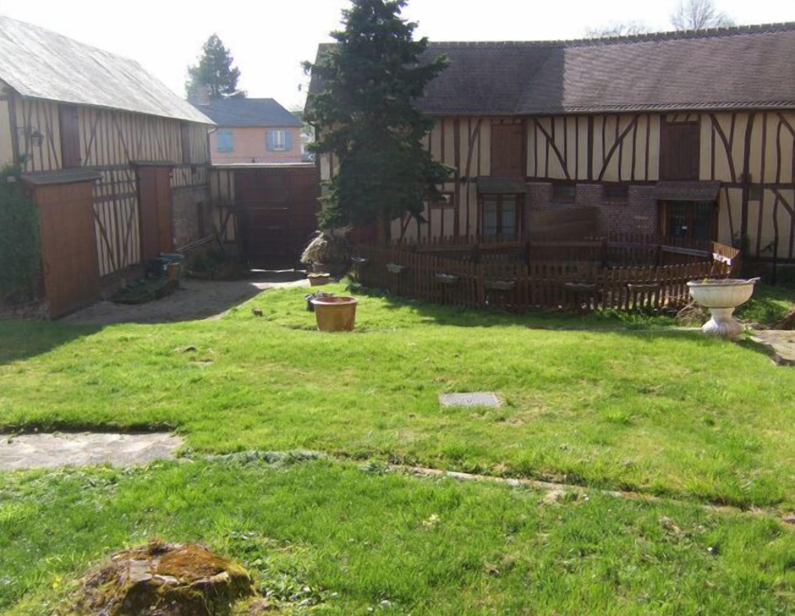 Ein Innenhof mit Rasenfläche, Holzzaun und einem großen Baum.