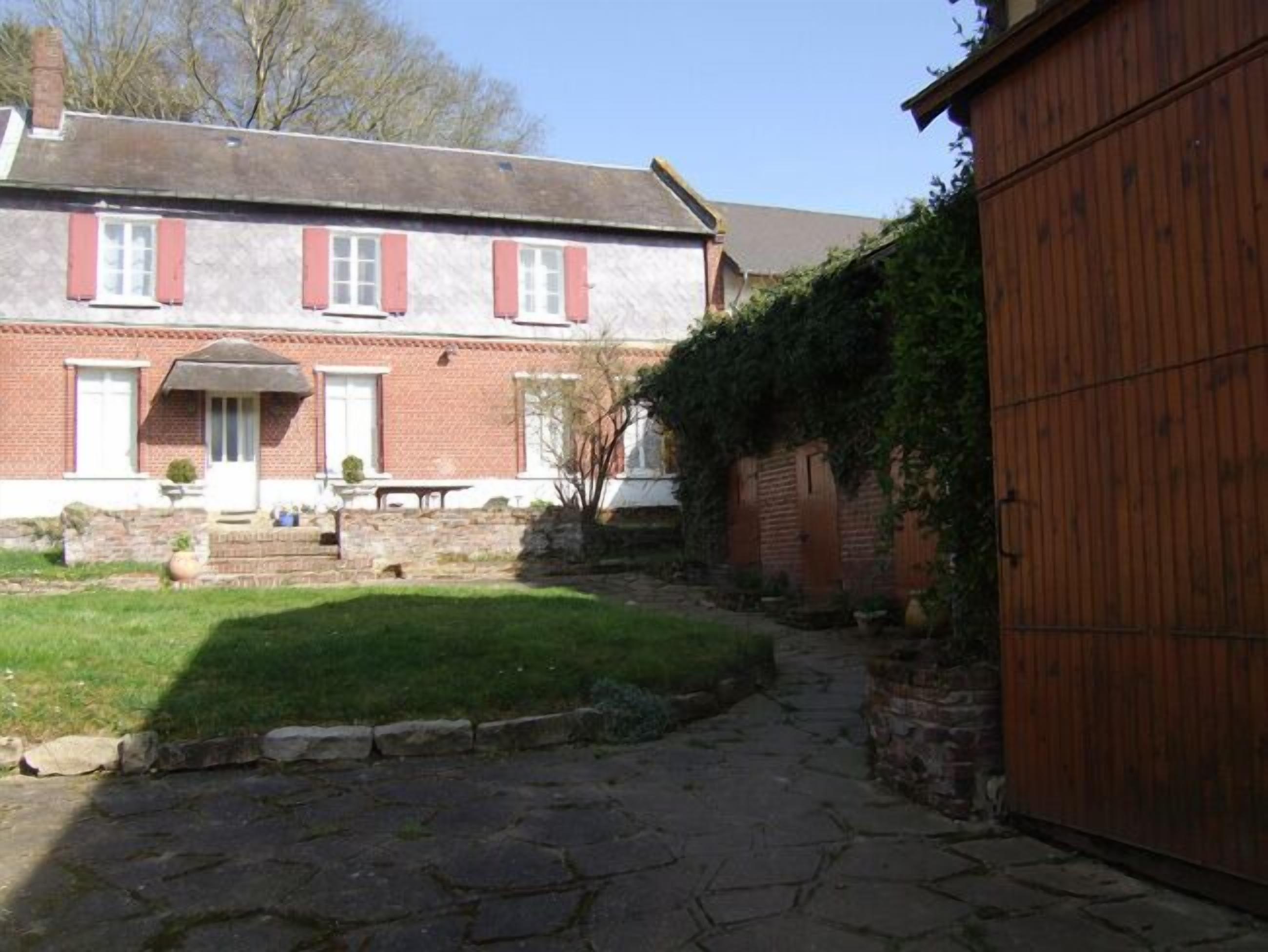 A brick house with a stone pathway leading to a wooden gate.