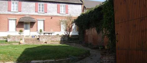 A brick house with a stone pathway leading to a wooden gate.