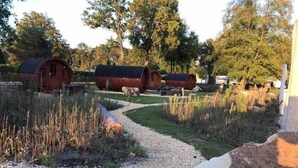 A gravel path leading to wooden cabins with a natural landscape and trees in the background. - Campingpark Heidewald (Sassenberg)