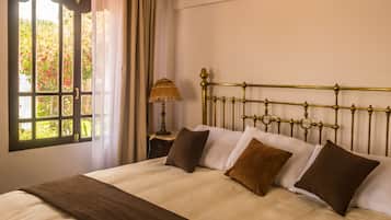A bedroom with a bed, a window with curtains, and a bedside table with a lamp.