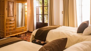 A hotel room with two beds, a wooden dresser, and a window with curtains. - El Jardin De Su Merced B&B (Sucre)