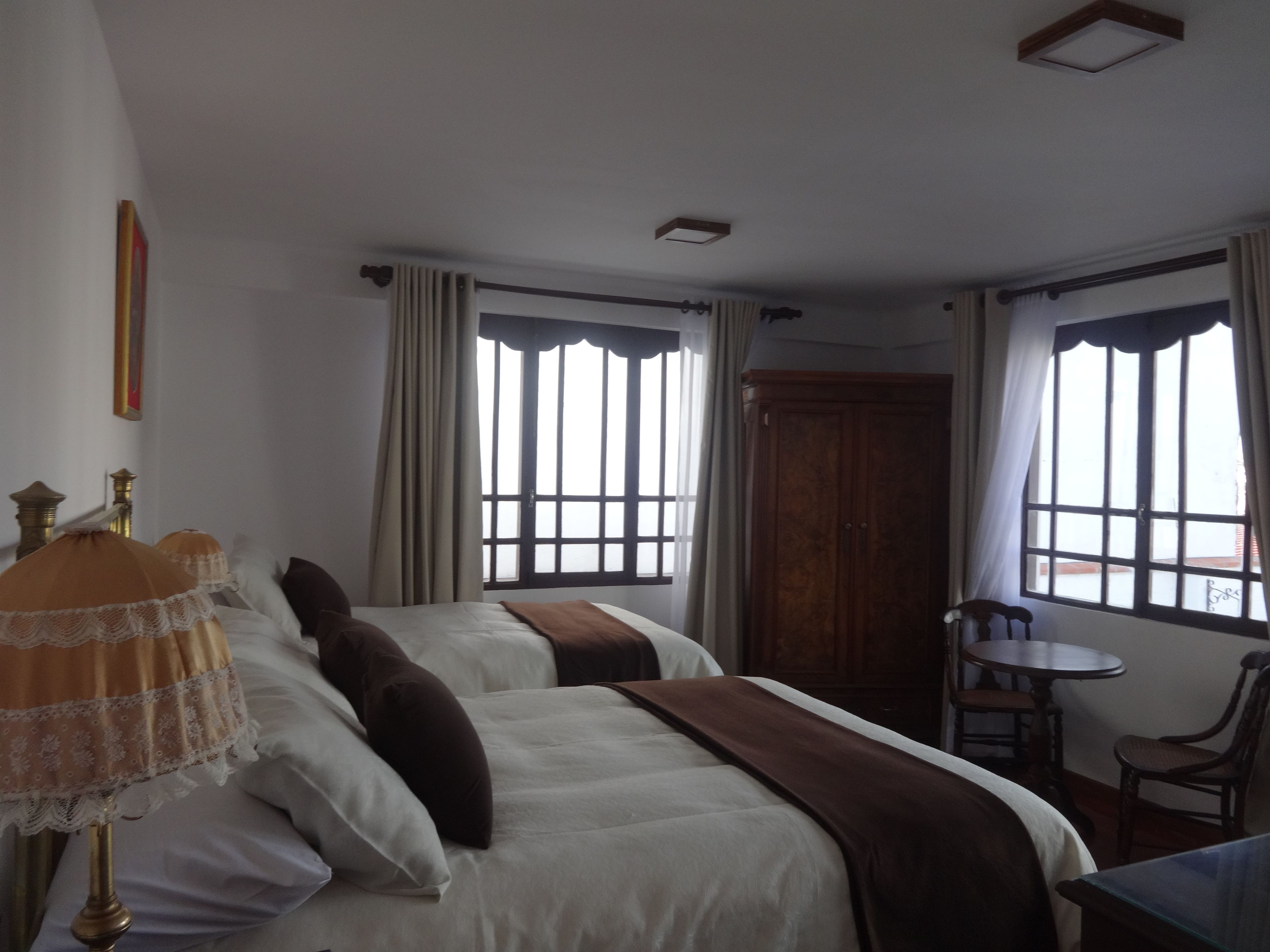 Habitación de hotel con dos camas, una mesita y una silla.