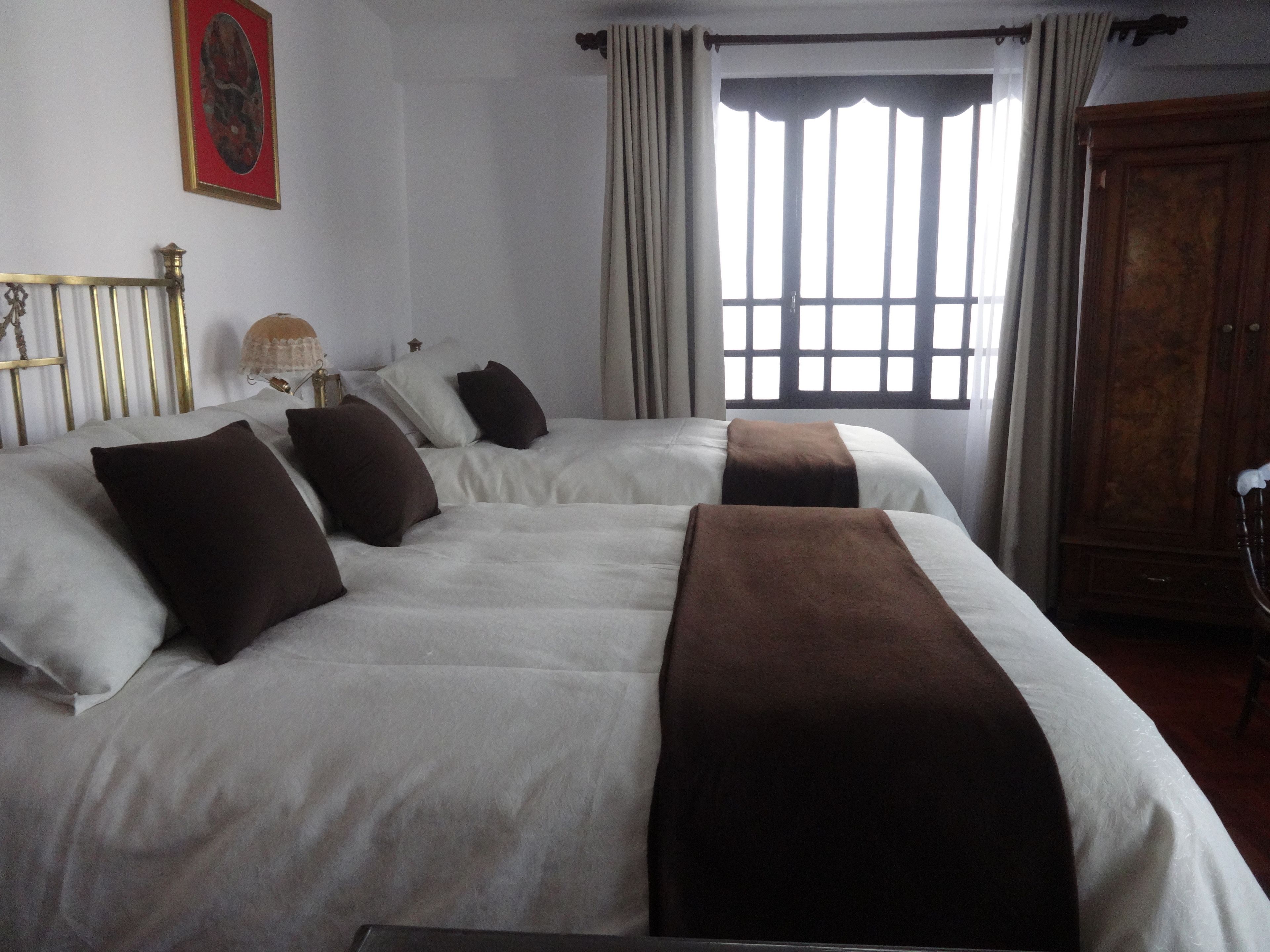 Een hotelkamer met een groot bed, een houten garderobe en een raam met gordijnen.