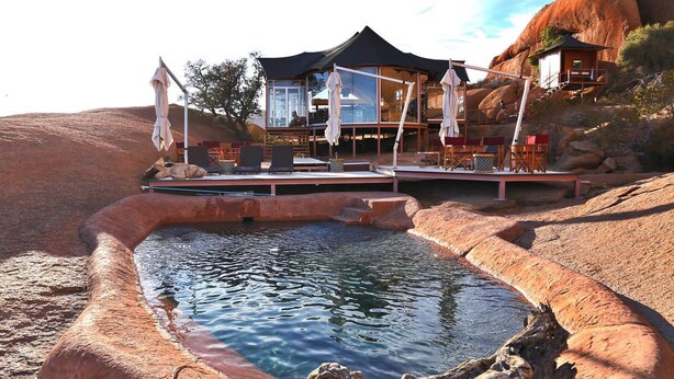 A resort with a pool, outdoor seating, and a large building with multiple levels. - Spitzkoppen Lodge (Usakos)