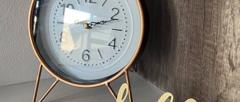 Un reloj de pared con detalles en latón y un cartel que dice 'hello' debajo.