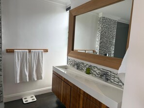 A bathroom with a wooden vanity, a white sink, and a large mirror. - Relaxed City Living (Gqeberha (Port Elizabeth))