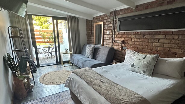 Un dormitorio moderno con una cama grande, un sofá, un televisor y un balcón.