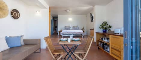 Un espacio habitable compacto con comedor, sofá, cama y kitchenette.