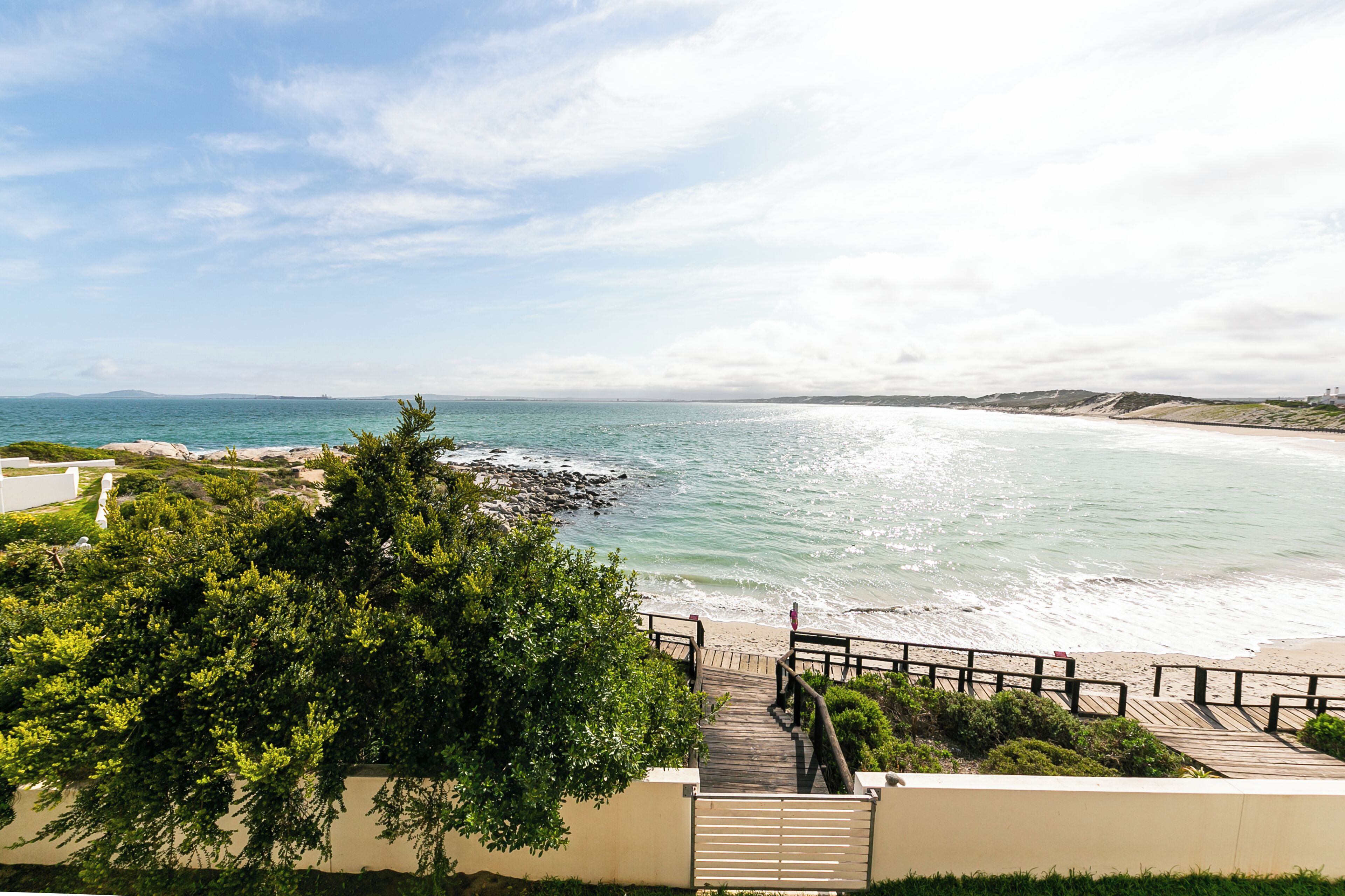 A coastal view with a wooden walkway leading to a beach.