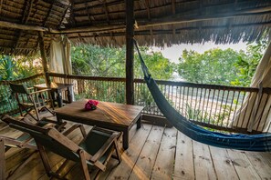 A wooden deck with a hammock, a table, and chairs. - Kitu Kiblu (Mafia Island)