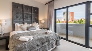 A modern hotel room with a large bed, a view of the city, and a balcony. - Lavira (Cape Town)