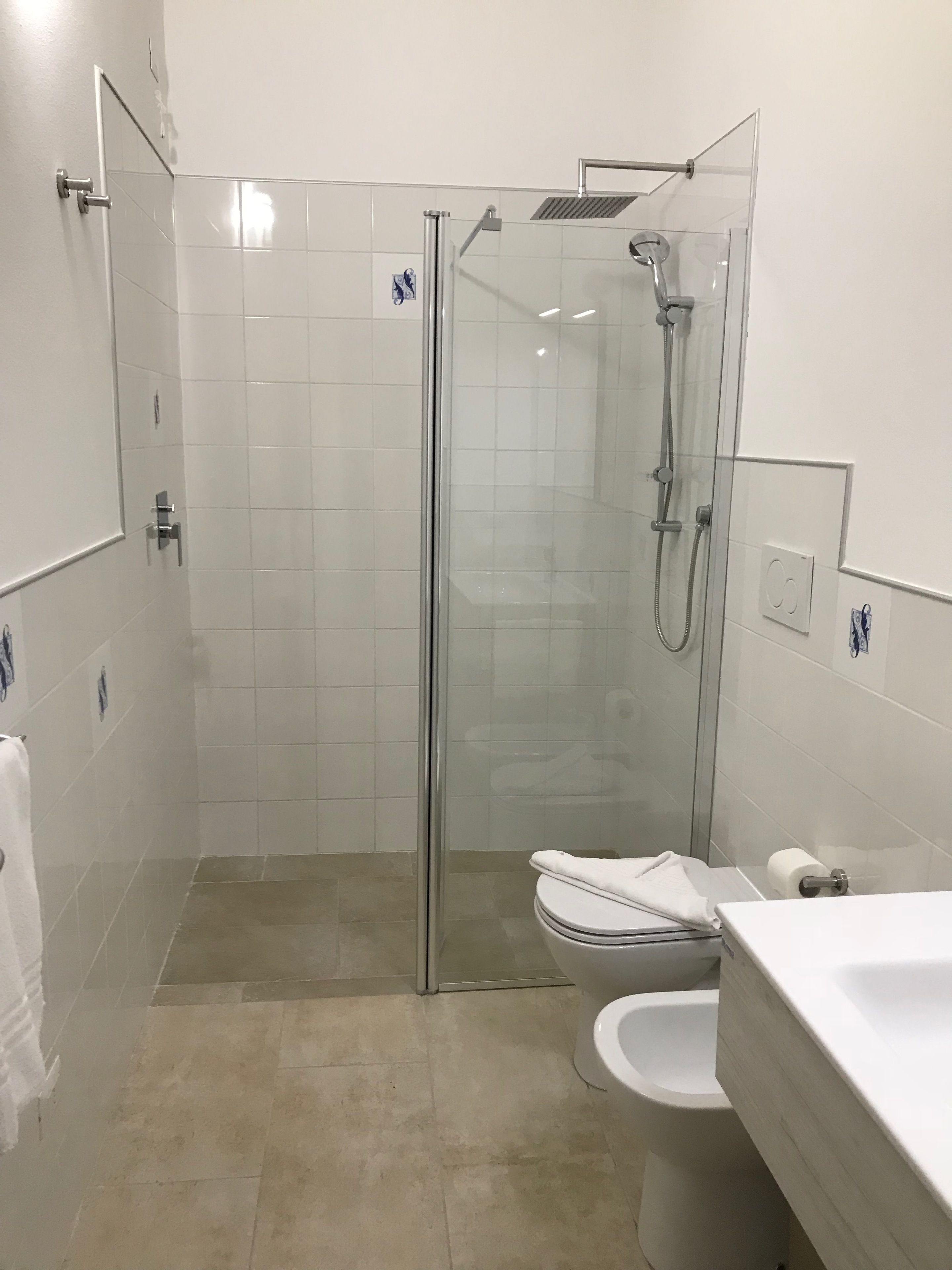 A modern bathroom with a glass-enclosed shower, a toilet, and a sink.