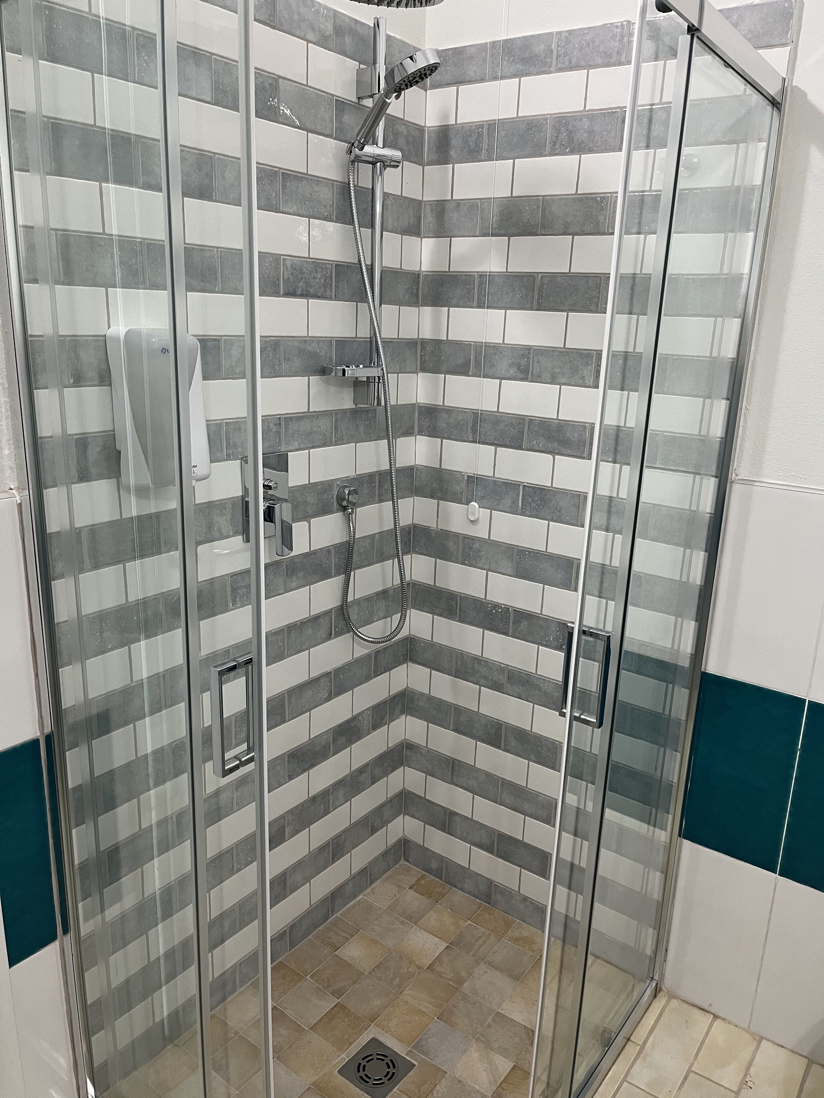A shower area with a glass door, tiled walls, and a corner showerhead.