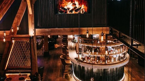 A rustic interior with exposed wooden beams, a central fireplace, and a circular bar area. - Cave Hotel & Golf Resort (Faversham)