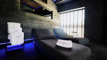 Un moderno cuarto de spa con pared de ladrillo, una camilla de masaje y una ventana con persianas.