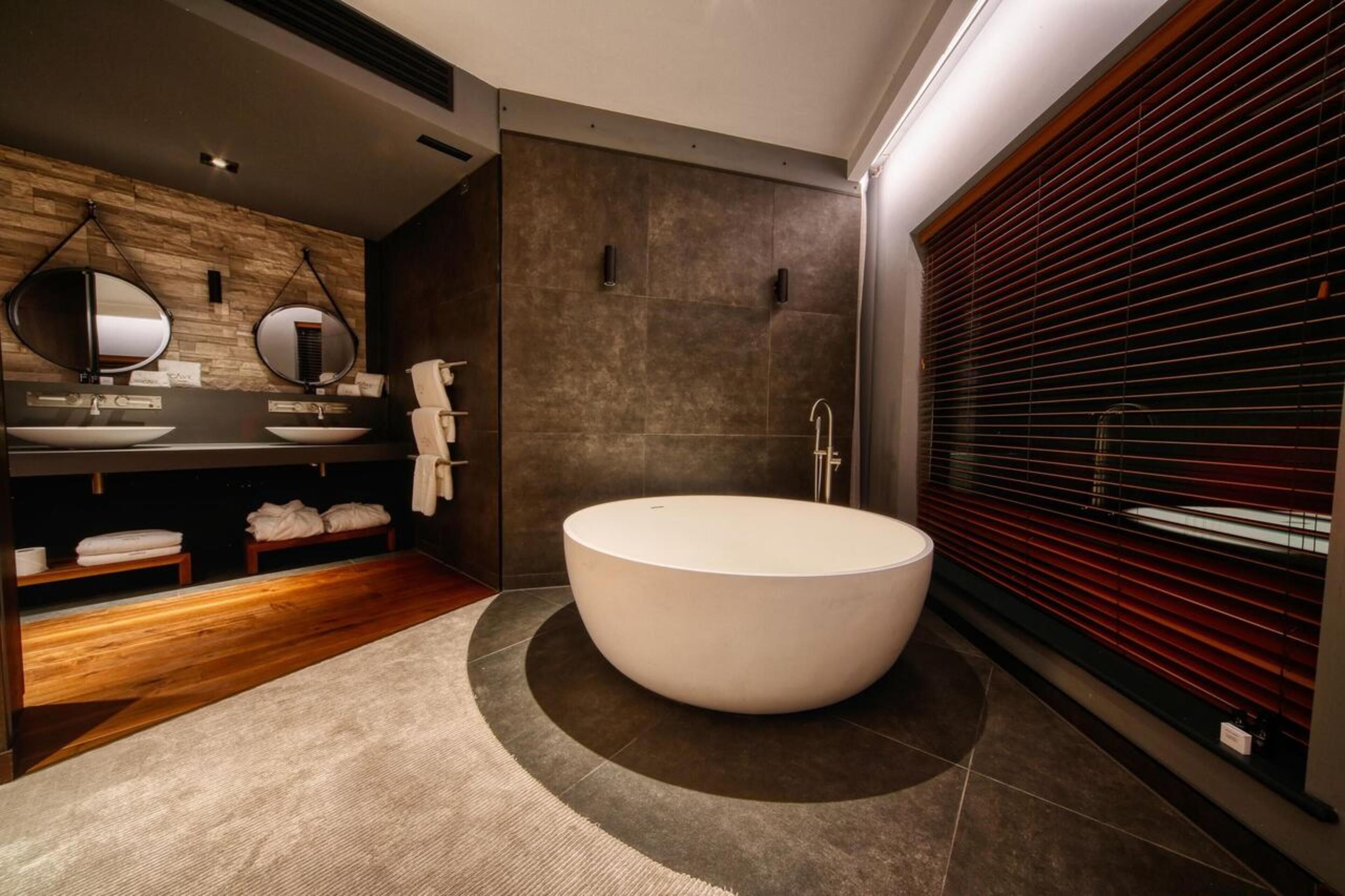 A modern bathroom with a freestanding bathtub, wooden vanity, and a large mirror.