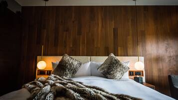 A neatly made bed with a fluffy blanket, two bedside lamps, and a wooden headboard.