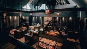 A modern interior with a high ceiling, exposed beams, and a cozy seating area with a fireplace. - Cave Hotel & Golf Resort (Faversham)