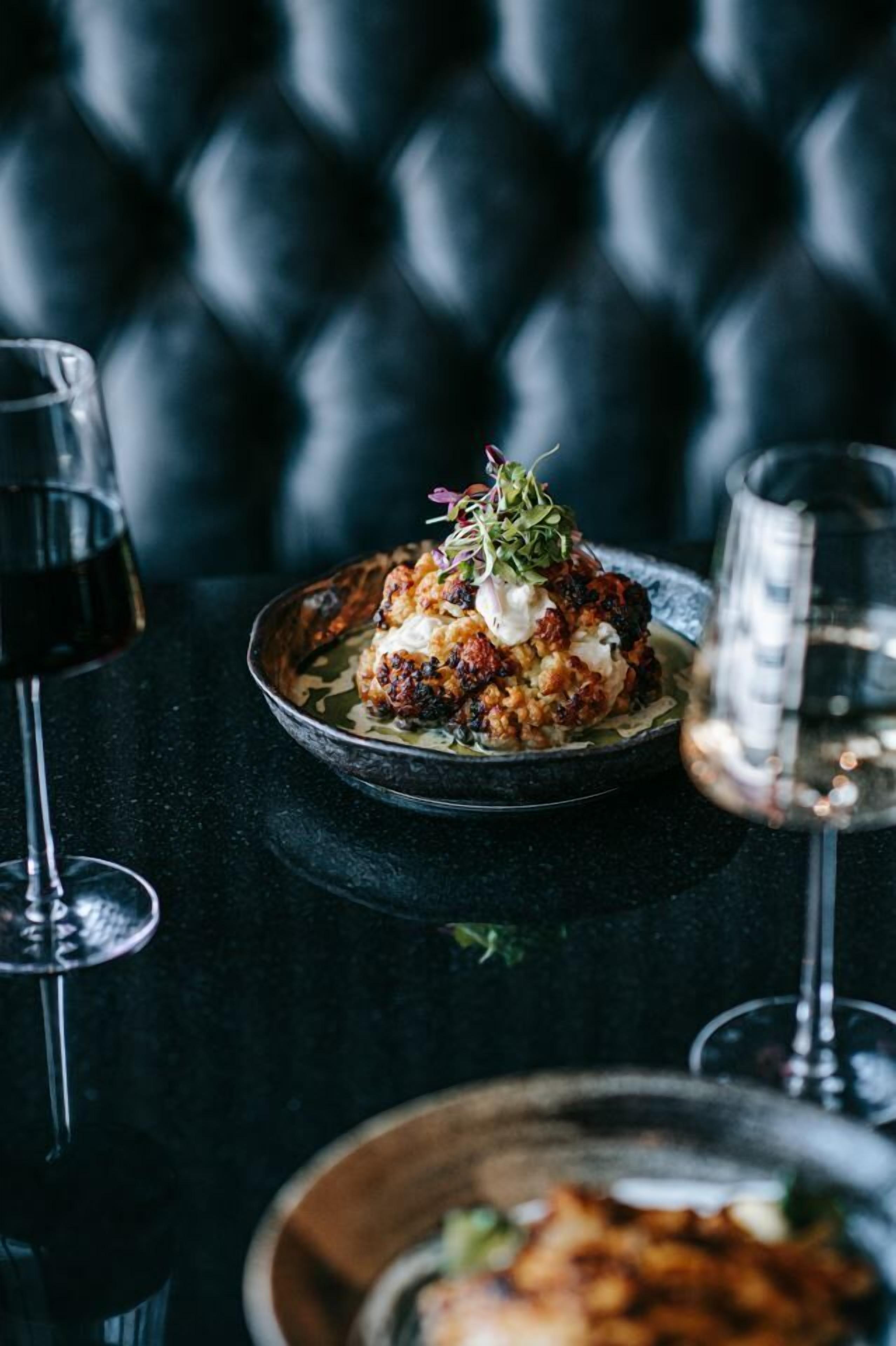 Uma mesa de jantar com um prato de comida e dois copos de vinho tinto.