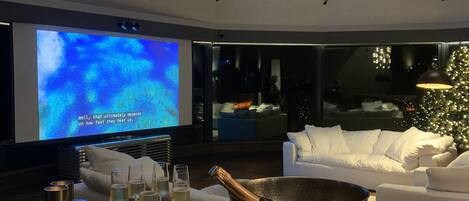 A modern living room with a large flat-screen TV, a white sofa, and a copper bowl on a table.