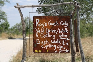 A sign indicating Roy's Guests Only Veld Drive/Walk & Cycling 10km and Bush Walk Cycling 4km. - Roy's Rest Camp (Grootfontein)