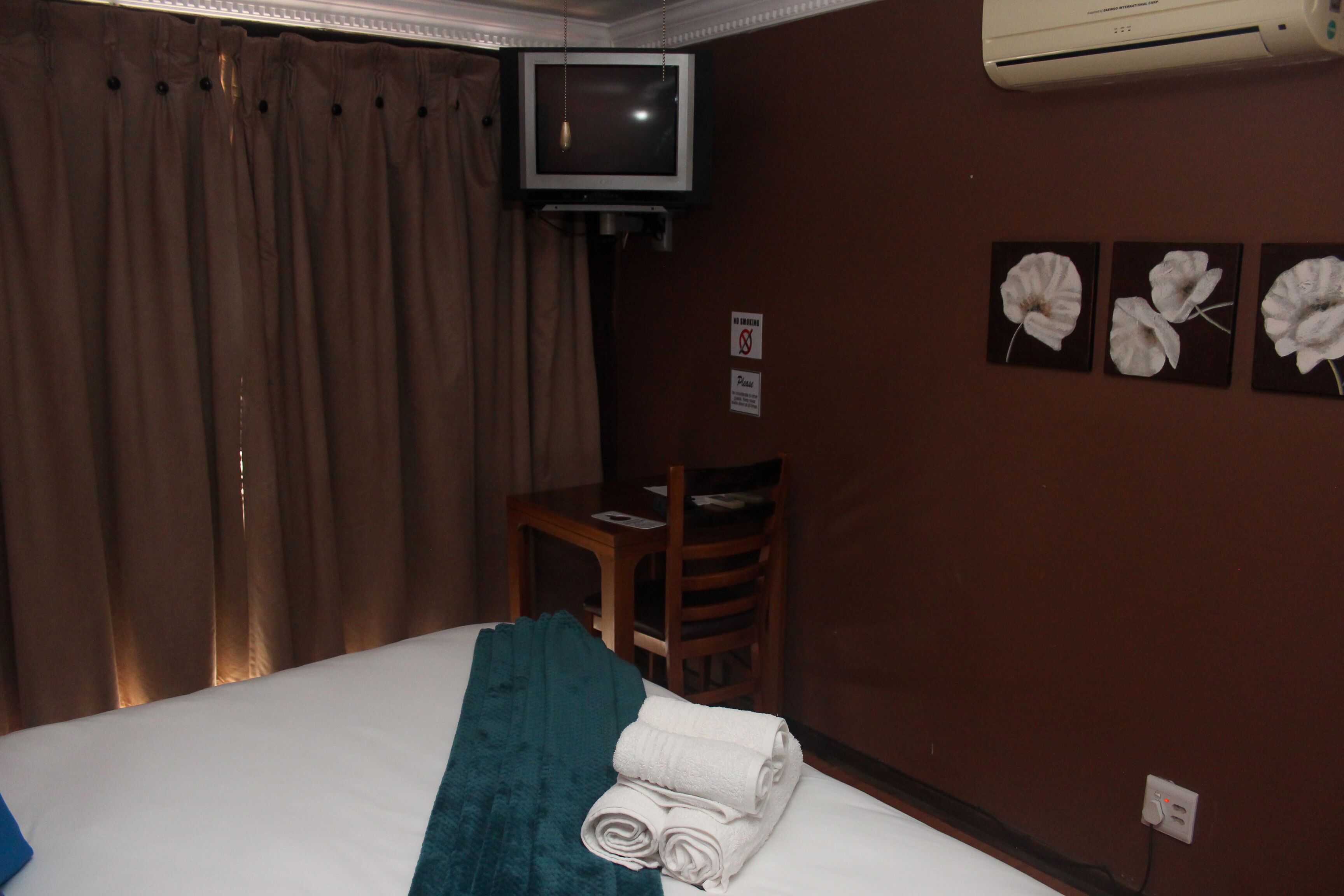 Ein Hotelzimmer mit Bett, Wandfernseher, Sessel und Tisch.