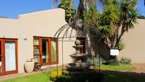 A building with a garden, a fountain, and a palm tree. - Echo Garden Guesthouse (Rustenburg)