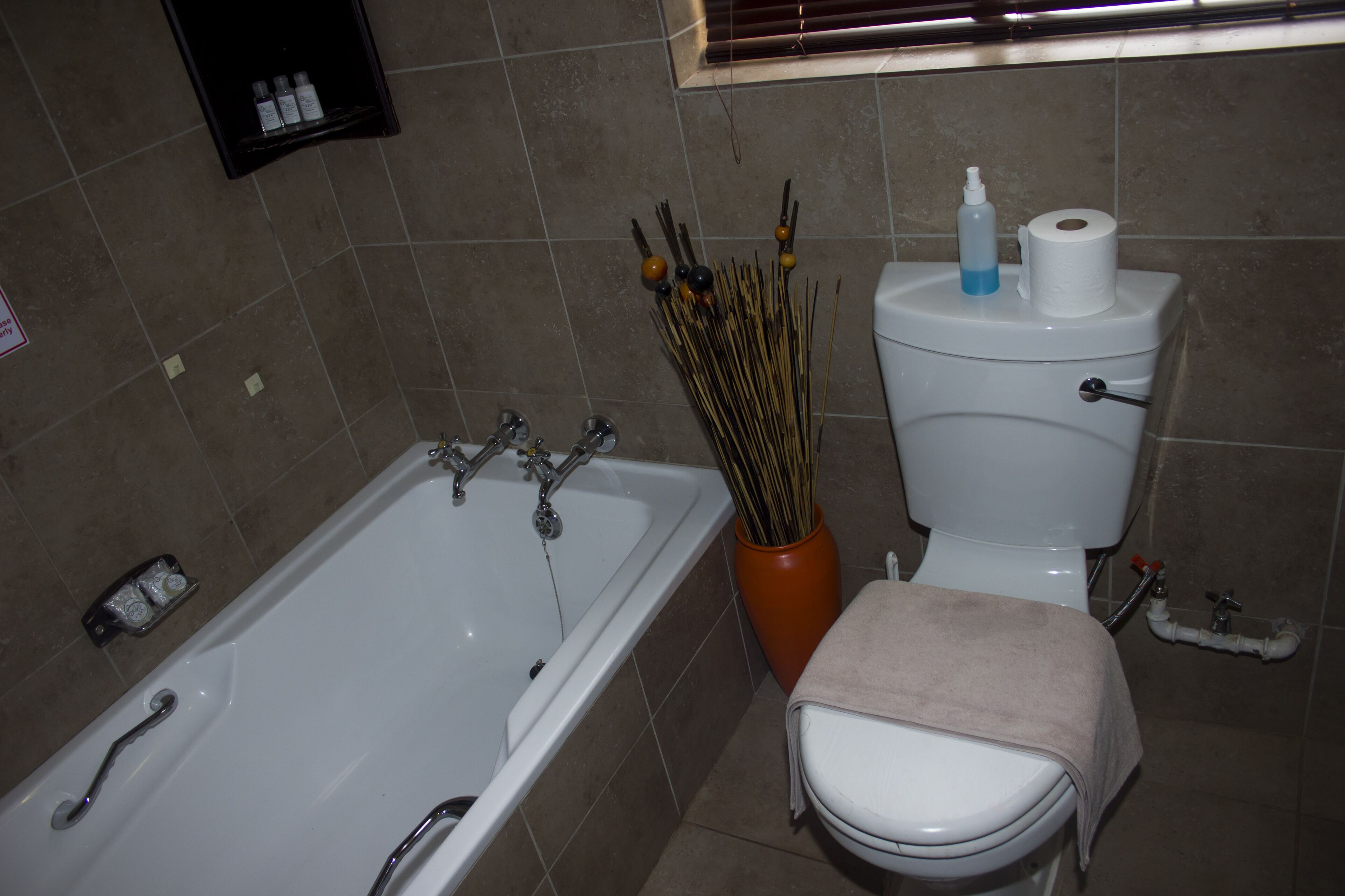A bathroom with a bathtub, toilet, and a window.