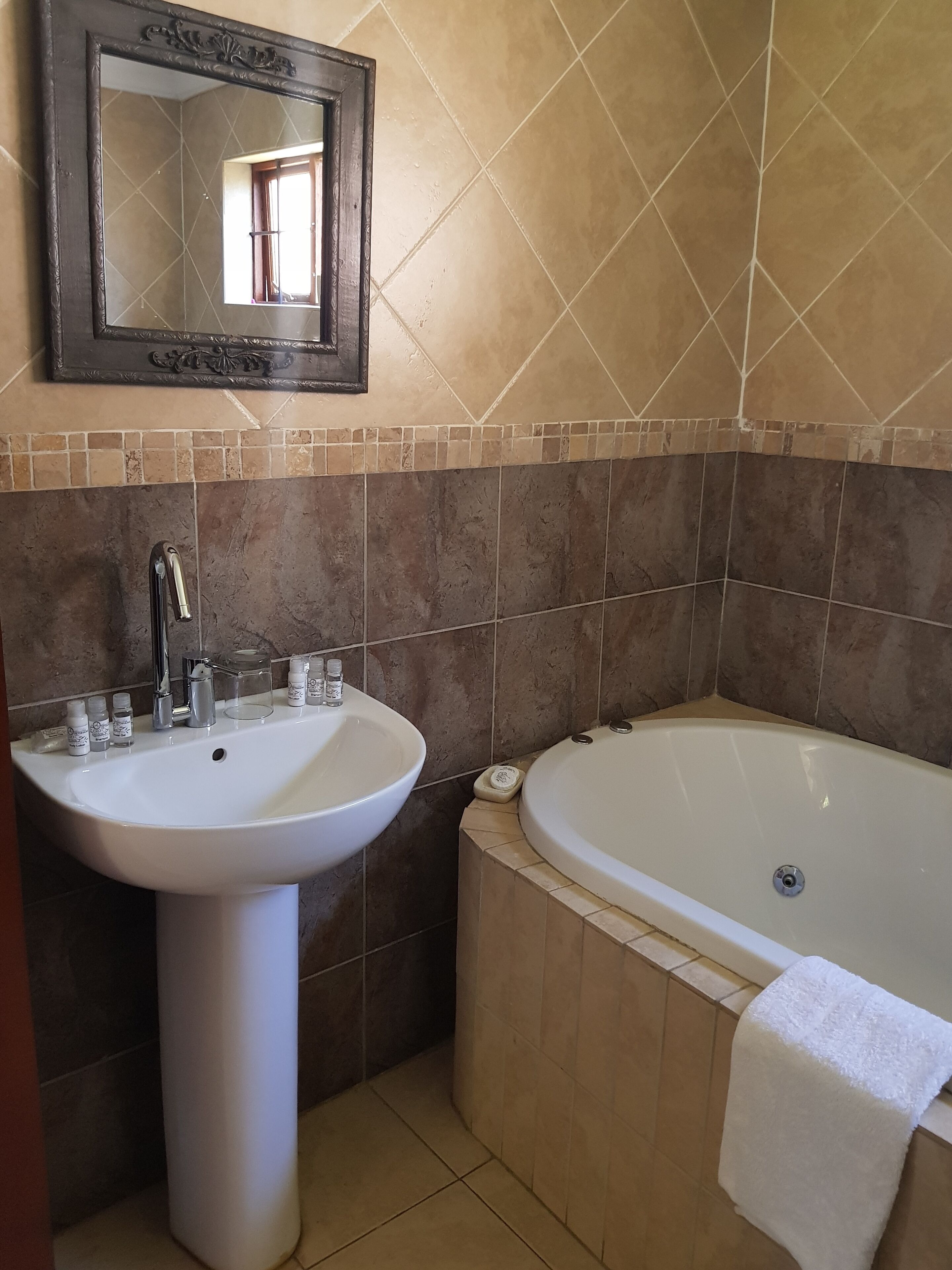 Une salle de bain avec un lavabo sur colonne, une baignoire et un miroir au mur.