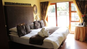 A neatly made bed with a headboard, a bedside lamp, and a window with curtains. - Echo Garden Guesthouse (Rustenburg)
