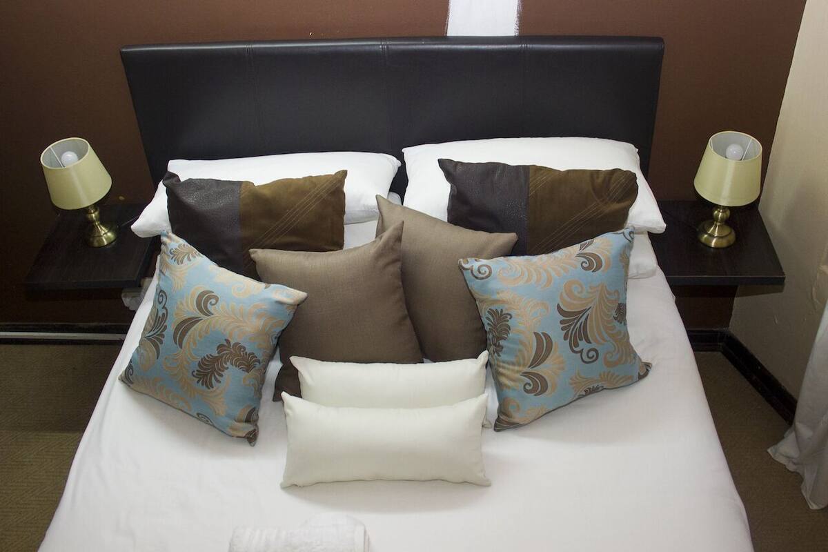 A neatly made bed with multiple pillows and two bedside lamps.