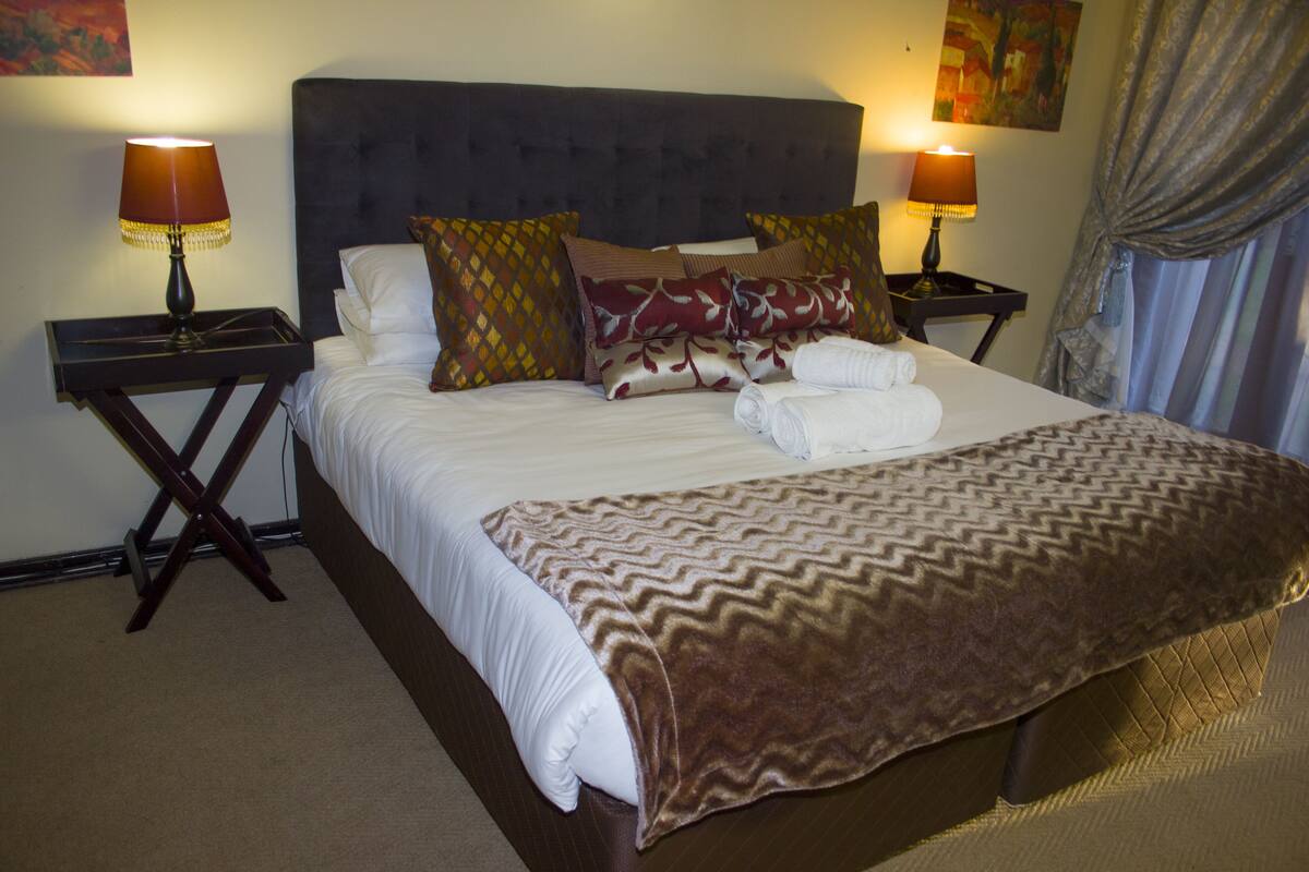 A neatly made bed with a brown patterned blanket, two bedside lamps, and a headboard.