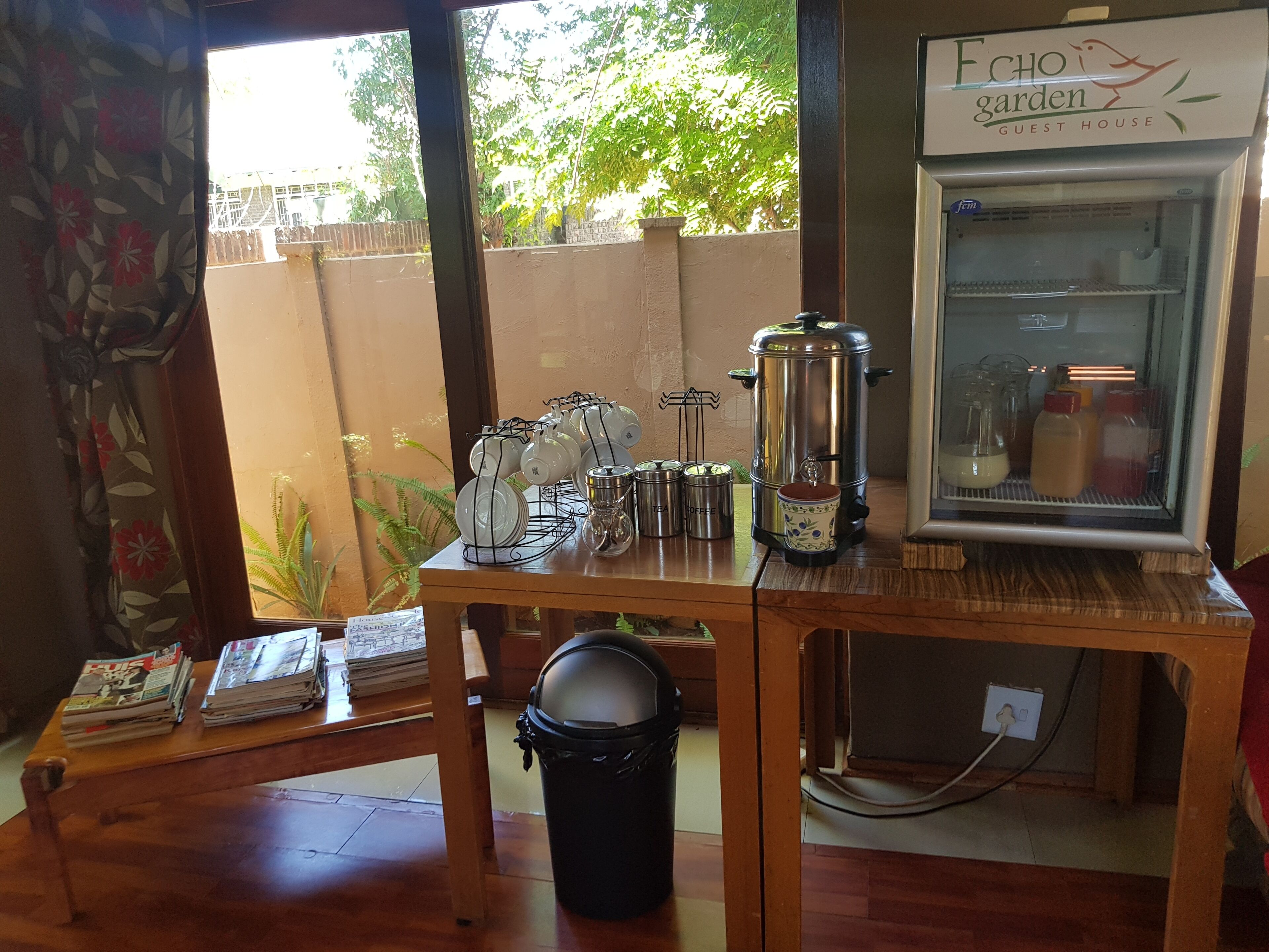 A kitchen area with a coffee maker, tea pots, and a refrigerator.