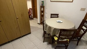 A dining area with a round table, chairs, and a cabinet. - Admiral Home (Venice)