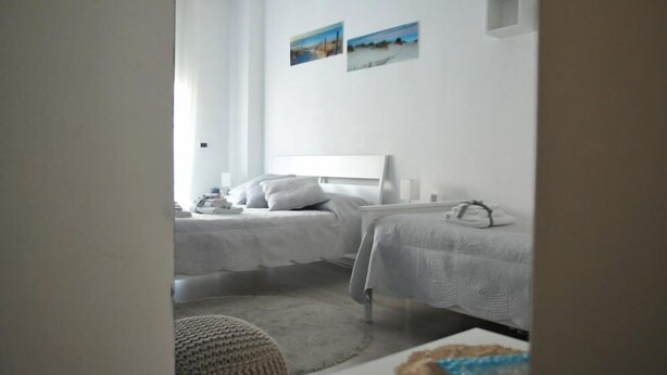 A hotel room with two single beds, a small table, and a chair. - B&B San Vitale (Bologna)