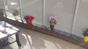 A balcony with a table and chairs, potted plants, and a mesh screen. - B&B San Vitale (Bologna)