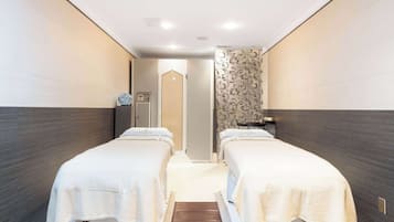 Two single beds with white linens, set side by side, in a stylishly decorated room.