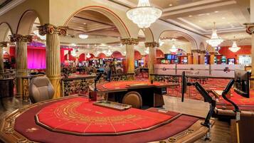 Experience the grandeur of our casino, featuring a large roulette table, decorative columns, and multiple gaming options.