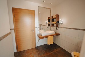 A bathroom with a wooden door, a white sink, a mirror, and a towel rack.