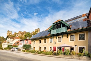 A building with solar panels on the roof, a sign for a restaurant, and a castle in the background.