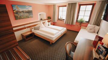 Een hotelkamer met een bed, een bureau, een stoel, een raam met gordijnen en een schilderij aan de muur.