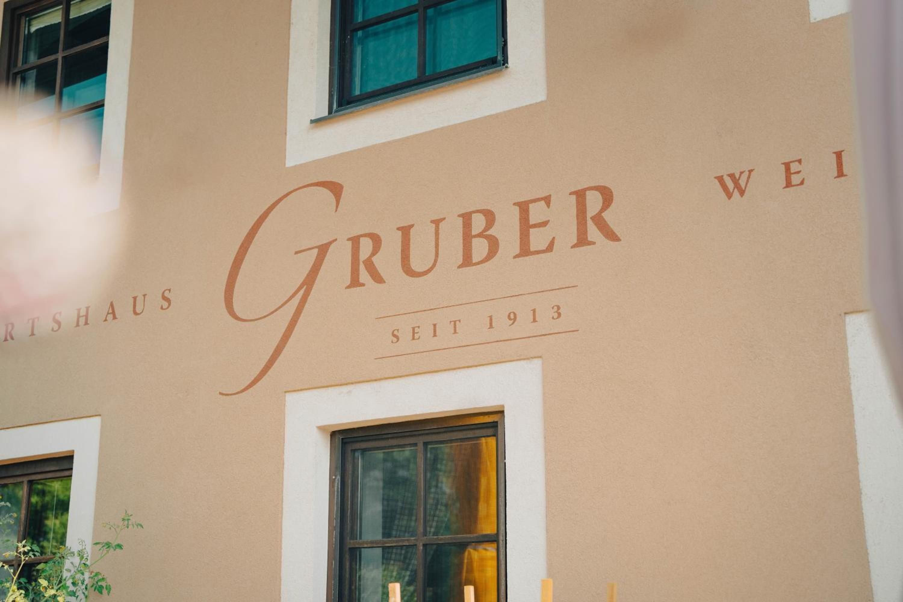 A building facade with the name 'Gruber Wei' and the year '1913' indicating the establishment year.